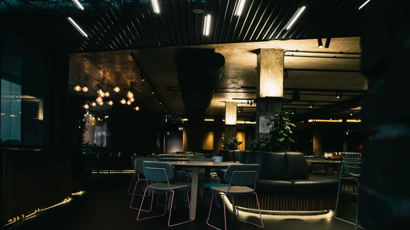 La salle du restaurant : tables en bois nappées, banquettes et lumière tamisée