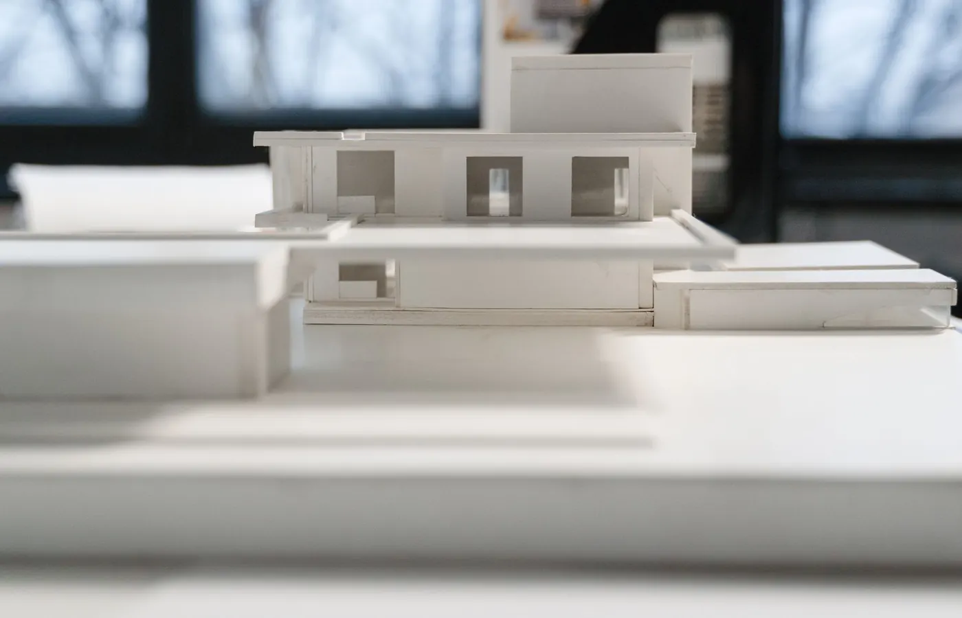 Maquettes d'étude en carton blanc posées sur une table de l'atelier, fenêtre en arrière-plan.