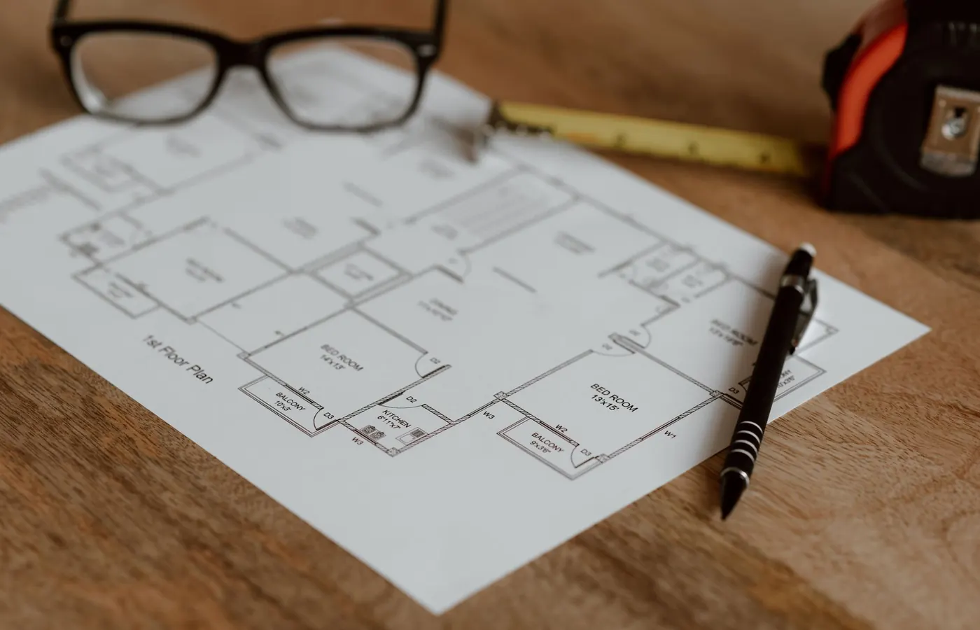 Plan de niveau tiré sur papier, posé sur une table de bois de l'atelier, une paire de lunettes à côté.