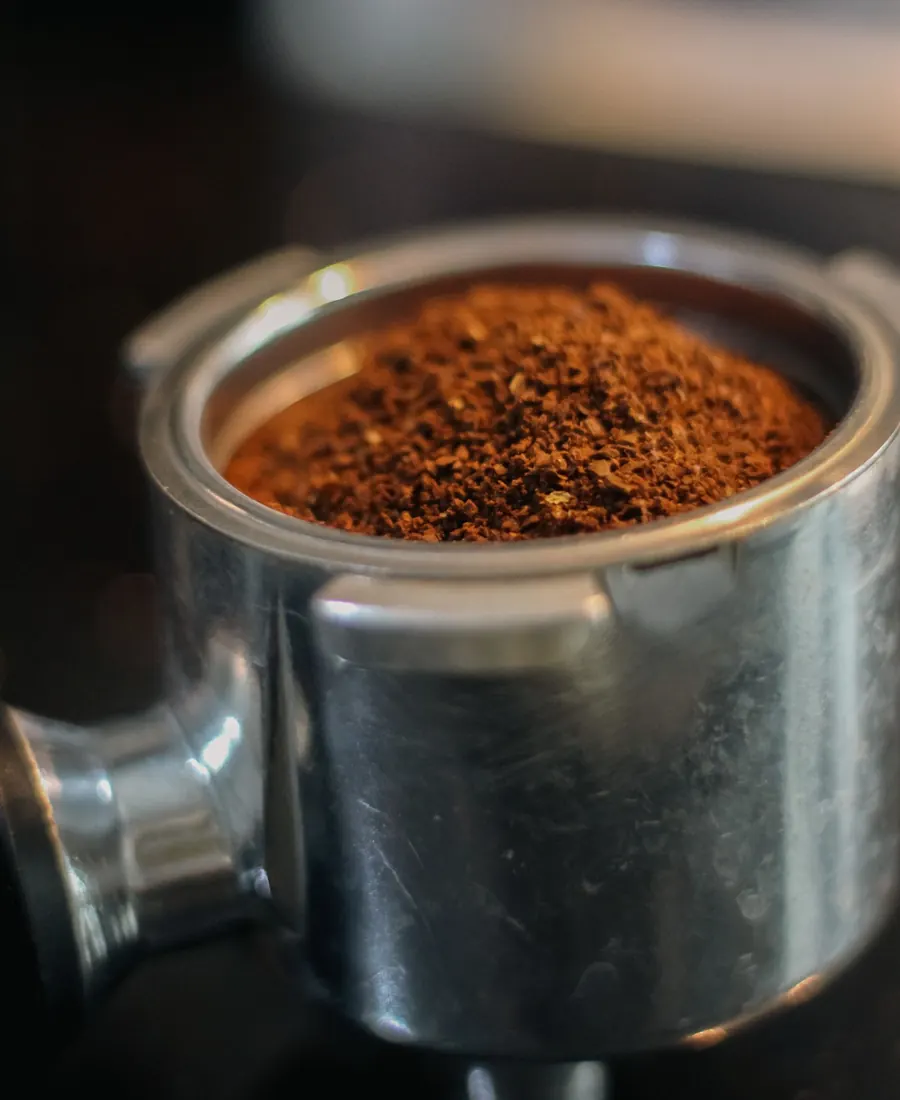Un porte-filtre rempli de café fraîchement moulu, prêt pour l’extraction